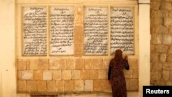 FILE - A displaced woman from the minority Yazidi sect, who fled violence in the Iraqi town of Sinjar, worships at their main holy temple in Lalish in Shikhan, Sept. 20, 2014. 
