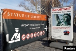 FILE - A sign announcing the closure of the Statue of Liberty, due to the U.S. government shutdown, sits near the ferry dock to the Statue of Liberty at Battery Park in Manhattan, New York, Jan. 20, 2018.