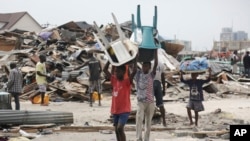 Des enfants transportent des chaises en plastique récupérées des maisons démolies et ince.ndiées par des fonctionnaires du gouvernement à Lekki, Lagos, au Nigeria, 12 novembre 2016