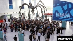 Activists march inside a conference center under a giant statue of a spider to demand urgent action to address climate change at the U.N. climate talks in Doha, Qatar, Friday, Dec. 7, 2012. 