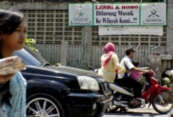 Pengendara motor melintas di depan spanduk bertuliskan penolakan terhadap kaum LGBT di kawasan Cigondewah Kaler, Bandung, Jawa Barat, 27 Januari 2016. (Foto: Reuters)