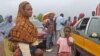 FILE- stranded people stand at a roadblock that separates Guinea and Sierra Leone.
