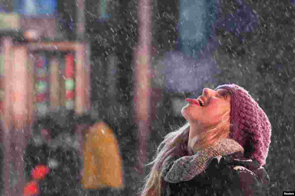 A tourist catches snowflakes on her tongue in Times Square, New York, Jan. 2, 2014. 