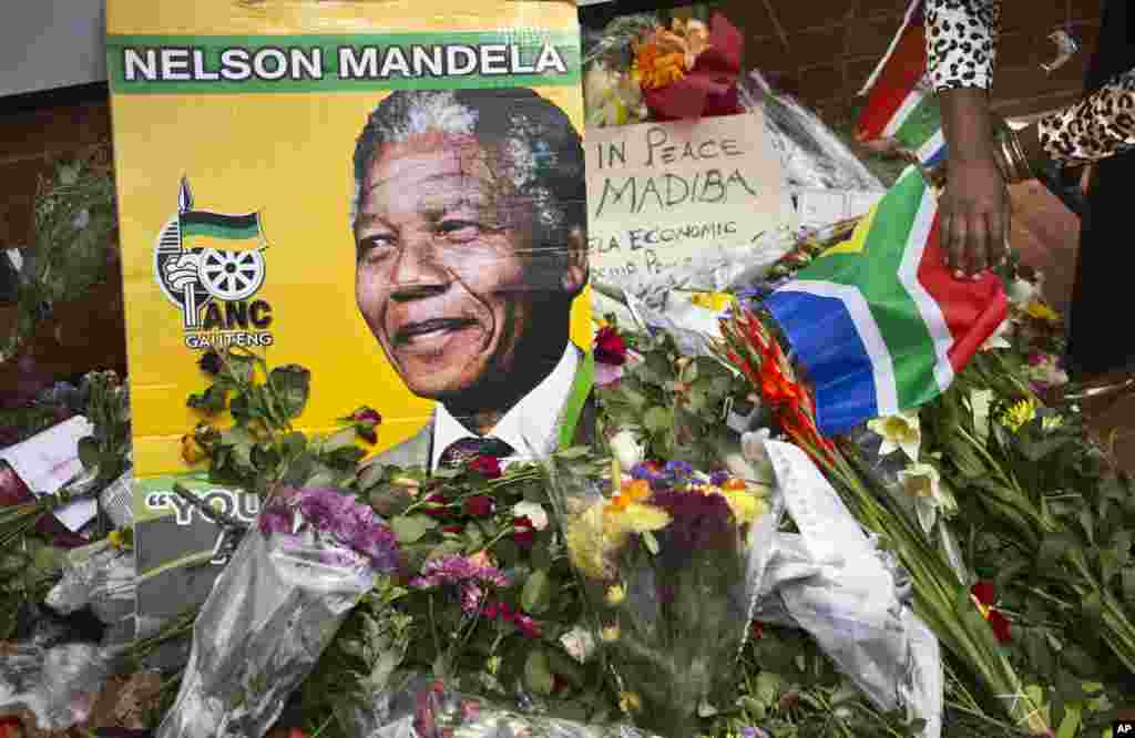 Flowers, posters, and messages left by mourners lie in front of Nelson Mandela's old house in Soweto, Johannesburg, South Africa, Saturday, Dec. 7, 2013.