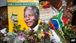 Flowers, posters, and messages left by mourners lie in front of Nelson Mandela's old house in Soweto, Johannesburg, South Africa, Saturday, Dec. 7, 2013.