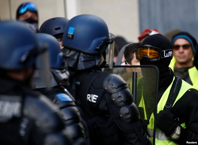 Protesters wearing yellow vests face riot police during a demonstration of the "yellow vest" movement in Angers, France, Jan. 19, 2019.