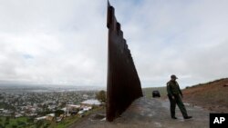 FILE - A Border Patrol agent walks near where the border wall ends that separates Tijuana, Mexico, left, from San Diego, right, Feb. 5, 2019.