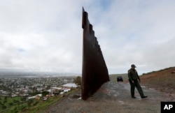 Border Patrol agent Vincent Pirro walks near where the border wall ends that separates Tijuana, Mexico, left, from San Diego, right, Feb. 5, 2019, in San Diego.