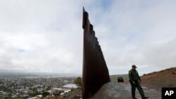 Border Patrol agent Vincent Pirro walks near where the border wall ends that separates Tijuana, Mexico, left, from San Diego, right, Feb. 5, 2019, in San Diego. 