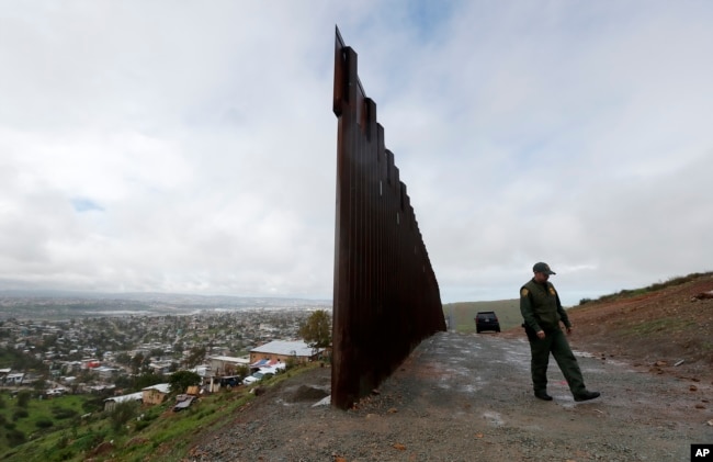 Border Patrol agent Vincent Pirro walks near where the border wall ends that separates Tijuana, Mexico, left, from San Diego, right, Feb. 5, 2019, in San Diego.