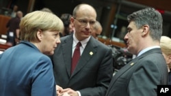 German Chancellor Angela Merkel, left, talks with Croatia's Prime Minister Zoran Milanovic, right, and Italy's Prime Minister Enrico Letta, during an EU summit at the European Council building in Brussels, Belgium, Dec. 19, 2013. 