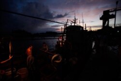 Para nelayan menurunkan ikan dari perahu mereka di sebuah desa nelayan di kota Tanmen, provinsi Hainan, di sebelah Laut China Selatan. (Foto: VOA)