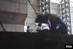 Workers at Western Mraine wear blue coveralls, yellow hard hats, heavy shoes, goggles and gloves. (A. Yee/VOA)