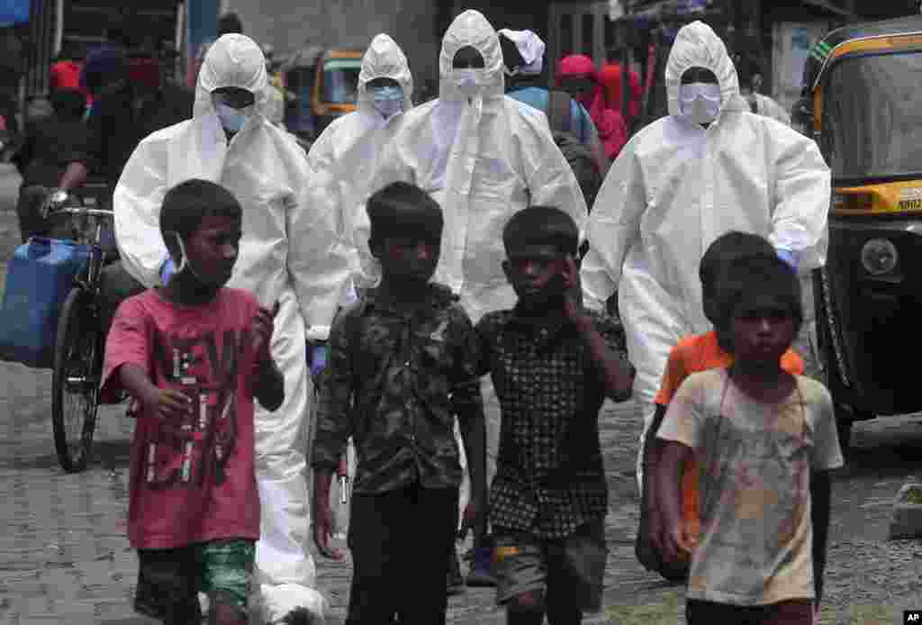 Health workers arrive to screen people for COVID-19 symptoms at a slum in Mumbai, India.