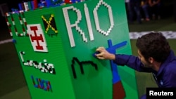 A man arranges LEGO bricks to build a Rio sign during a LEGO presentation of a massive model of the city including the Olympic sites at the Media Center in Rio de Janeiro, Brazil, Aug. 1, 2016. 