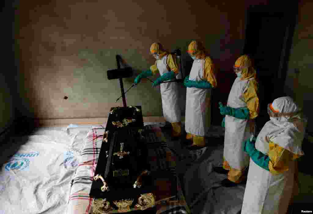 A healthcare worker sprays a room during a funeral of Kavugho Cindi Dorcas who is suspected of dying of Ebola, in Beni, North Kivu Province of Democratic Republic of Congo, Dec. 9, 2018.
