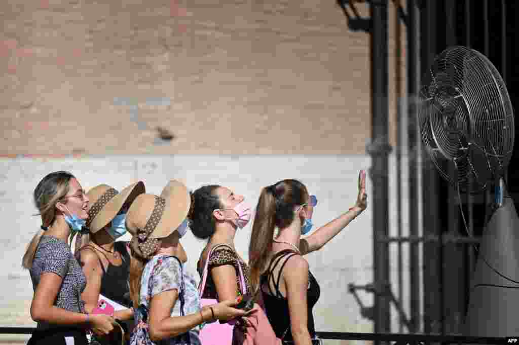 A group of woman cool off in front of a cooling fan during a heatwave as they queue at the enterance of the Colosseum in Rome, Italy.