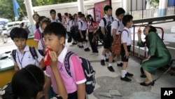  Thai teachers check the mouth of the students for hand, foot and mouth disease, before they get inside the school in Bangkok, July 25, 2012. 