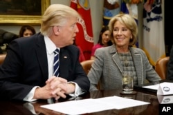 FILE - President Donald Trump talks to Education Secretary Betsy DeVos in the Roosevelt Room of the White House in Washington, Feb. 14, 2017.