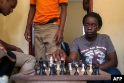 FILE - Phiona Mutesi, then 18, plays a game of chess with her colleagues at the chess academy in Kibuye, Kampala, Jan. 26, 2015.