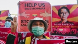 Seorang demonstran memberi hormat tiga jari sambil memegang tanda untuk memprotes kudeta militer dan menuntut pembebasan pemimpin terpilih Aung San Suu Kyi, di Yangon, Myanmar, 12 Februari 2021. (Foto: Reuters)