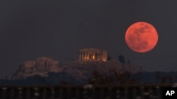 FILE - A super blue blood moon rises behind the 2,500-year-old Parthenon temple on the Acropolis of Athens, Greece, on Wednesday, Jan. 31, 2018. The longest lunar eclipse of the century will happen late July 27 or early July 28, depending on where you live. (AP Photo/Petros Giannakouris)