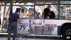 Israeli police officers examine a damaged bus at the site of a bombing in Tel Aviv, Israel, November 21, 2012.