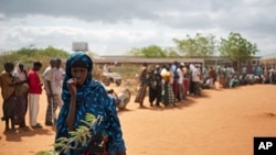 A Somali woman stands in front of Somalis queuing outside the reception center in Ifo refugee camp, one of three camps in Kenya's Dadaab refugee complex on July 25, 2011