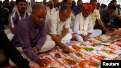 FILE - Indian businessmen write religious verses on their record-keeping books as part of a ritual to worship the Hindu deity of wealth in the western Indian city of Ahmedabad, Nov. 3, 2013. Hindu groups oppose a Sharia-compliant international bank's plan to operate in India.
