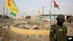 FILE - A soldier of the Kurdish Democratic Party (KDP) patrols at a destroyed roundabout in the town of Snuny, close to Sinjar, northern Iraq, Jan. 29, 2015. The KDP has been using crossings at the Iraq-Syria border as a tool to exert political pressure on its historical rivals that dominate the Syrian Kurdish region.