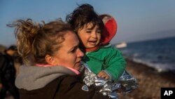 A volunteer holds a baby after her family's arrival on a dinghy from the Turkish coast to the northeastern Greek island of Lesbos on Nov. 17, 2015.