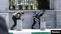 Members of Iranian forces take cover during an attack on the Iranian parliament in central Tehran, Iran, June 7, 2017. 