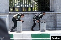 FILE - Members of Iranian forces take cover during an attack on the Iranian parliament in central Tehran, Iran, June 2017.