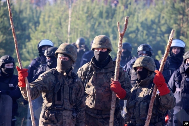 Polish police and border guards stand near barbed wire to stop migrants from the Middle East and elsewhere gathering at the Belarus-Poland border near Grodno, Belarus, Nov. 9, 2021.