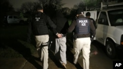 FILE - U.S. Immigration and Customs Enforcement agents make an arrest in Dallas. Three people were charged with human trafficking in Houston, Texas, after 12 migrants were left in a sweltering truck for hours.