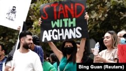 Paris Sharifie, seorang imigran Afghanistan-Amerika yang berasal dari Herat, membawa spanduk bertuliskan "Stand With Afghans" saat demonstrasi di pusat kota Los Angeles, California, AS, 21 Agustus 2021. (Foto: REUTERS/Bing Guan)