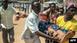 Men carry a woman who passed out as heavy gunfire was directed towards the Baya Dombia school where voters had gathered to cast ballots in a constitutional referendum, in Bangui, CAR, Dec. 13, 2015.