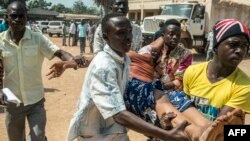 Une victime de récentes violences secourue par des hommes près d'un bureau de vote lors du référendum, à Bangui, Centrafrique, 13 décembre 2015.