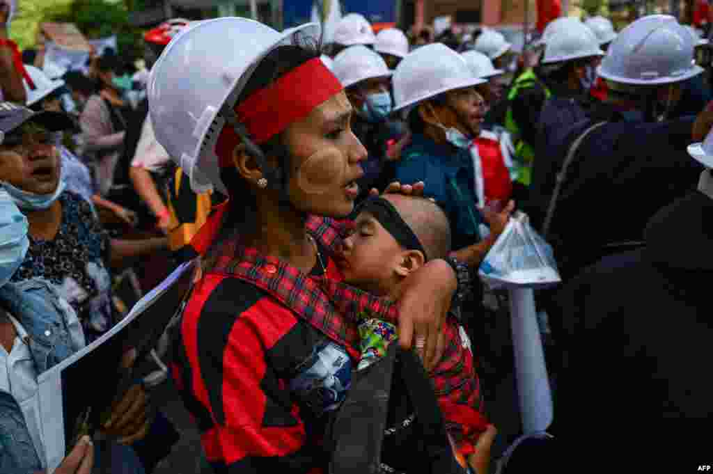 A protester carrying a child, marches during a demonstration against the February 1 military coup in Yangon, Myanmar.