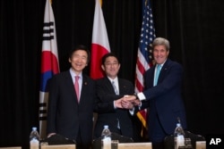 Minister of Foreign Affairs Yun Byung-se of South Korea, left, Minister of Foreign Affairs Fumio Kishida of Japan, and U.S. Secretary of State John Kerry join hands during a meeting between the three leaders Sunday, Sept. 18, 2016, in New York .
