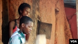 Aid worker Soloman Okoduwa (front) and resident Joy Joy Eriamentor (behind) listen to Naomi Benjamin tell her story. (VOA/Heather Murdock)