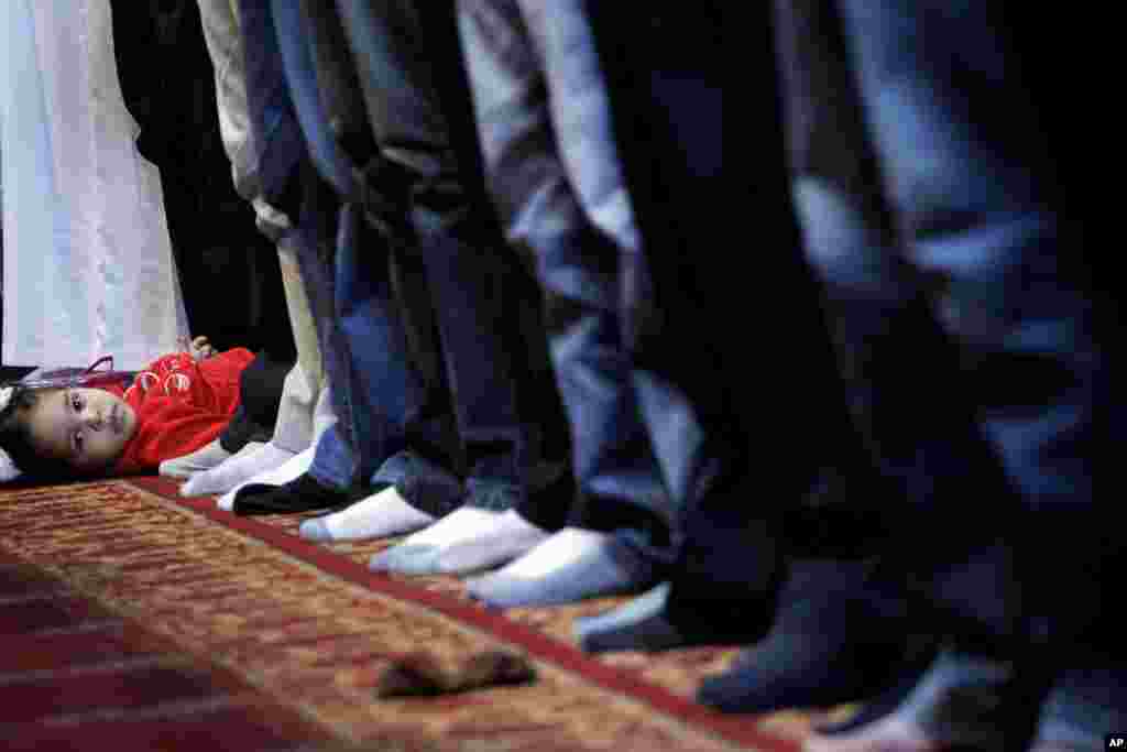 A child lies on down the floor during an Eid al-Adha prayer at an indoor hall in the Athens suburb of Moschato, Greece, October 26, 2012. 