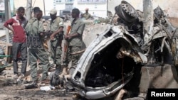 Officers stand by the remains of a wrecked car at the scene of car bomb explosion along the "Kilometre 4" road junction, south of the capital Mogadishu, Somalia, May 5, 2013.