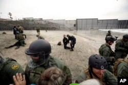 A woman is detained during a protest in San Diego, near the border with Tijuana, Mexico, Dec. 10, 2018.