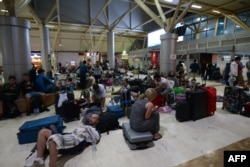 Foreign tourists sleep on the floor as they wait to depart from the Praya Lombok International Airport on the West Nusa Tenggara province on August 6, 2018.