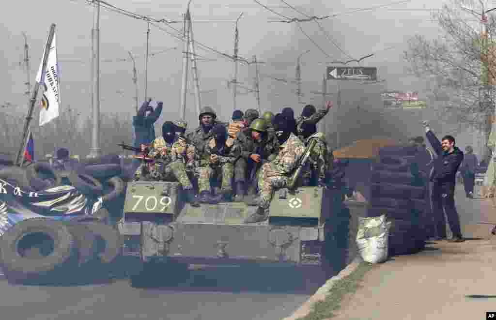 A combat vehicle with gunmen on top makes its way through a checkpoint to the town of Slovyansk, Ukraine, April 16, 2014. 
