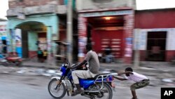 Un enfant fait du roller derrière une moto, Port-au-Prince, 25 octobre 2015