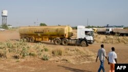 Photo d’archives (2 mars 2014) : Deux hommes marchent près des champs pétrolifères de Paloch dans l’État du Nil supérieur, au Soudan du Sud, près de la frontière avec le Soudan. (AFP PHOTO / Ally NGETHI)