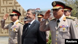 Egypt's President Mohamed Morsi (C) stands after laying a wreath during his visit to the tomb of former President Anwar al-Sadat and the Tomb of the Unknown Soldier during the commemoration of Sinai Liberation Day in Cairo, April 24, 2013.