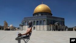 Seorang demonstran Palestina mengenakan masker, memegang batu saat berlangsungnya bentrokan dengan pasukan keamanan Israel di kompleks Masjid Al Aqsa di Kota Tua Yerusalem, Jumat, 18 Juni 2021. (AP Photo/Mahmoud Illean)